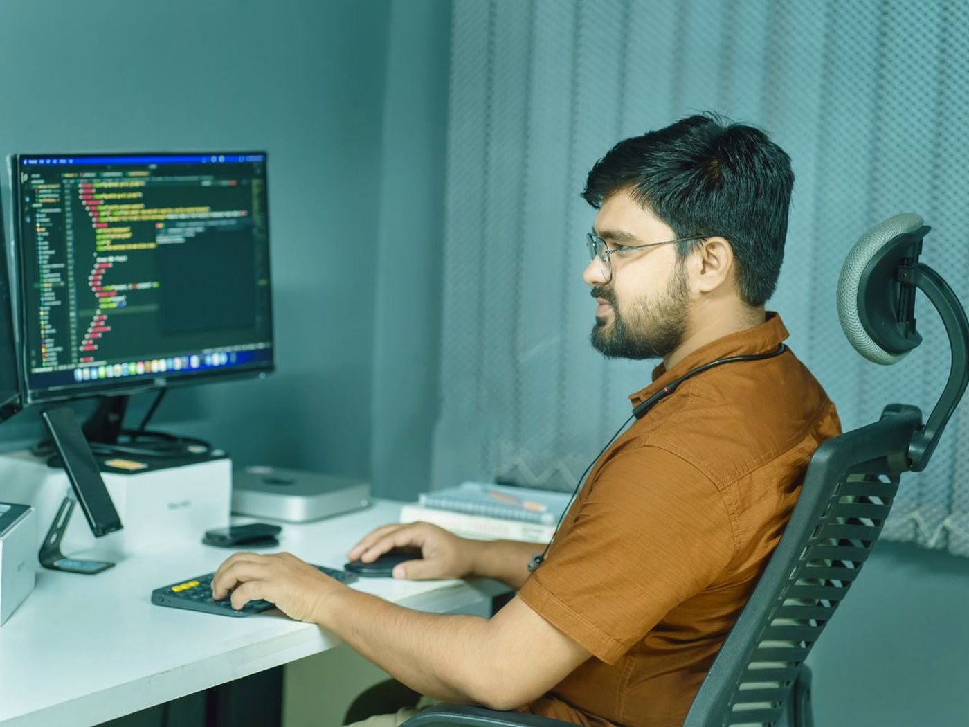 Un développeur à son bureau, de profil, devant un écran de code