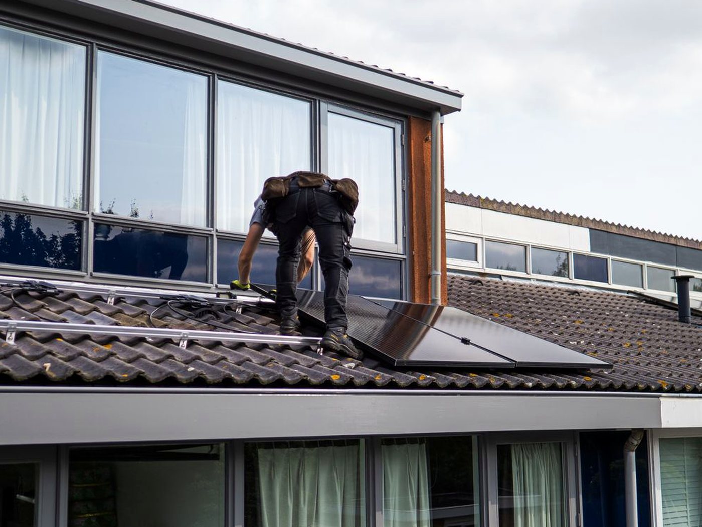 Un artisan pose des panneaux solaires sur le toit d’une maison