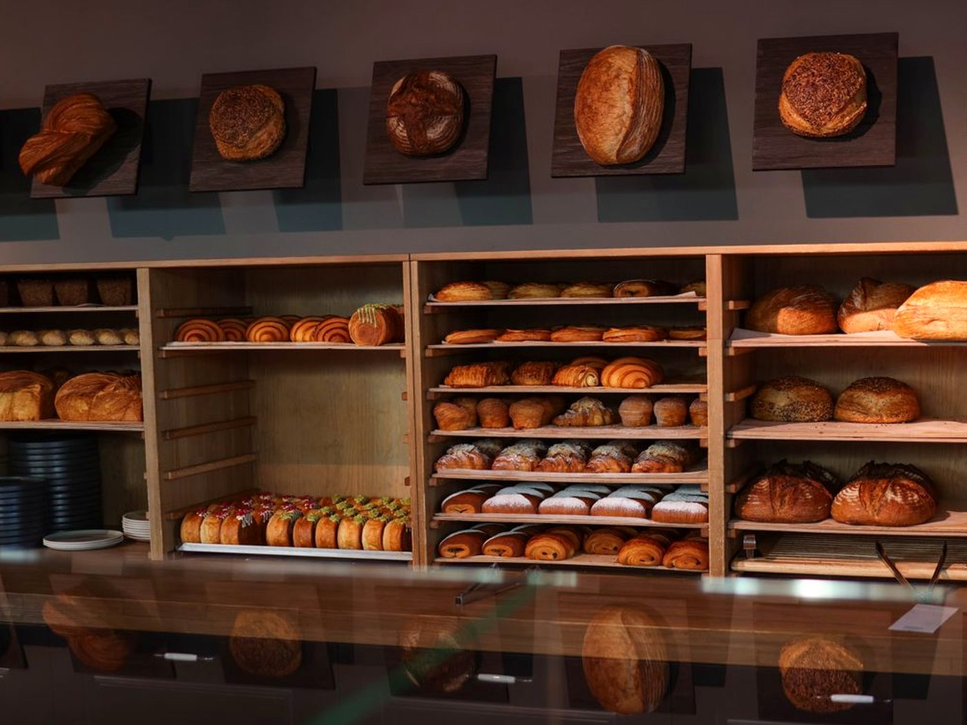 Des pains et des viennoiseries rangés sur les étagères en bois d’une boulangerie