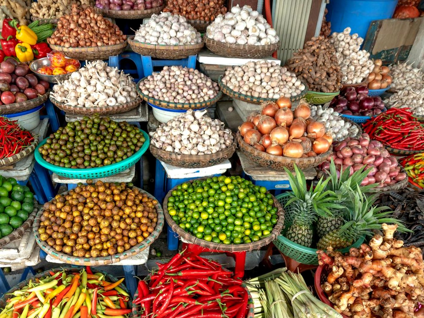 Des paniers d’ail, d’oignons, d’échalotes, de piments et de citrons verts sur un étal de marché
