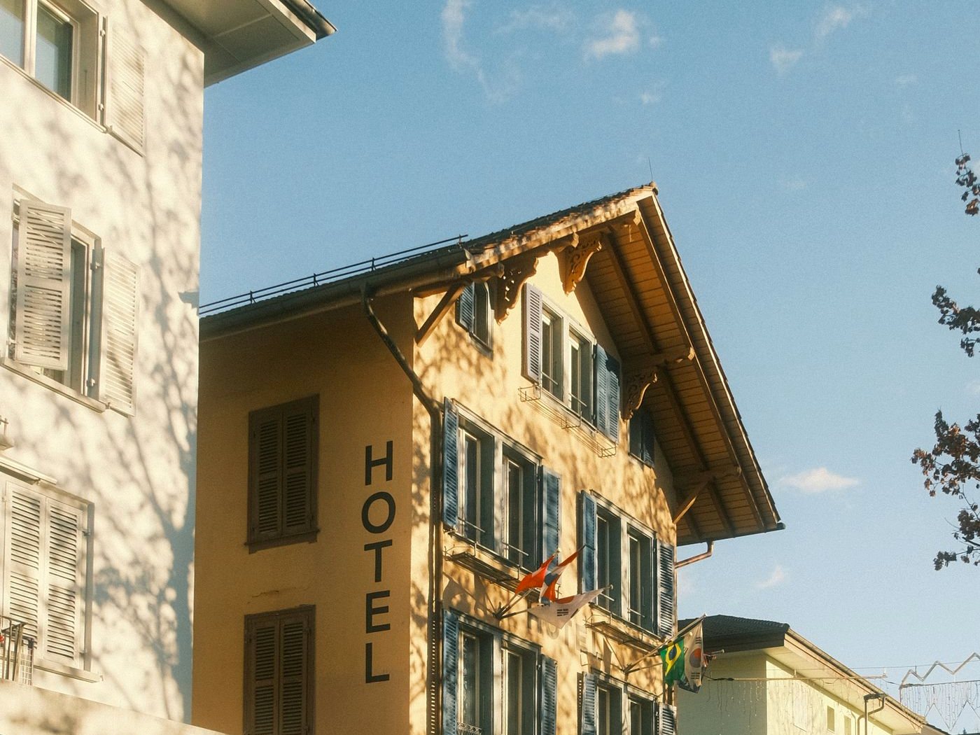 La façade ensoleillée d’un hôtel aux volets bleus