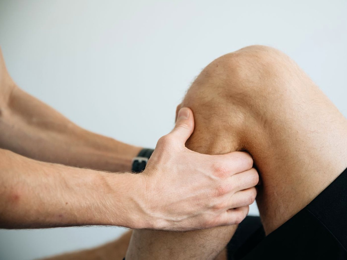 La main d’un praticien masse le genou d’un patient